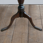 An early 19th century oak tripod table with baluster column and circular tray top.
